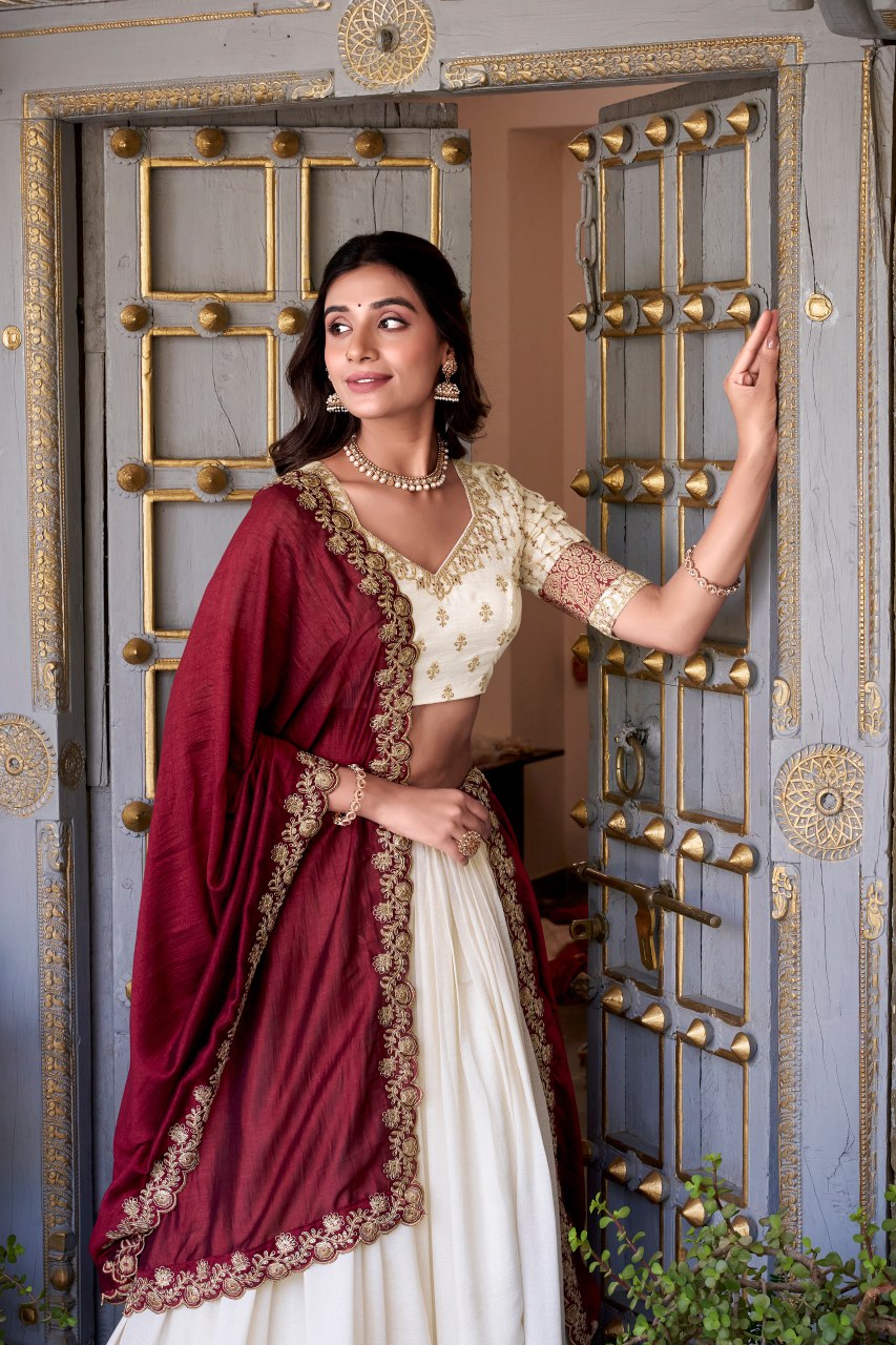 Off-white Vichitra silk lehenga choli set featuring zari weaving, sequins lace border, and embroidered dupatta ideal for weddings and festive celebrations.